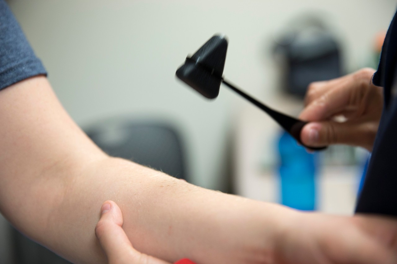 Reflex hammer tool being used on arm