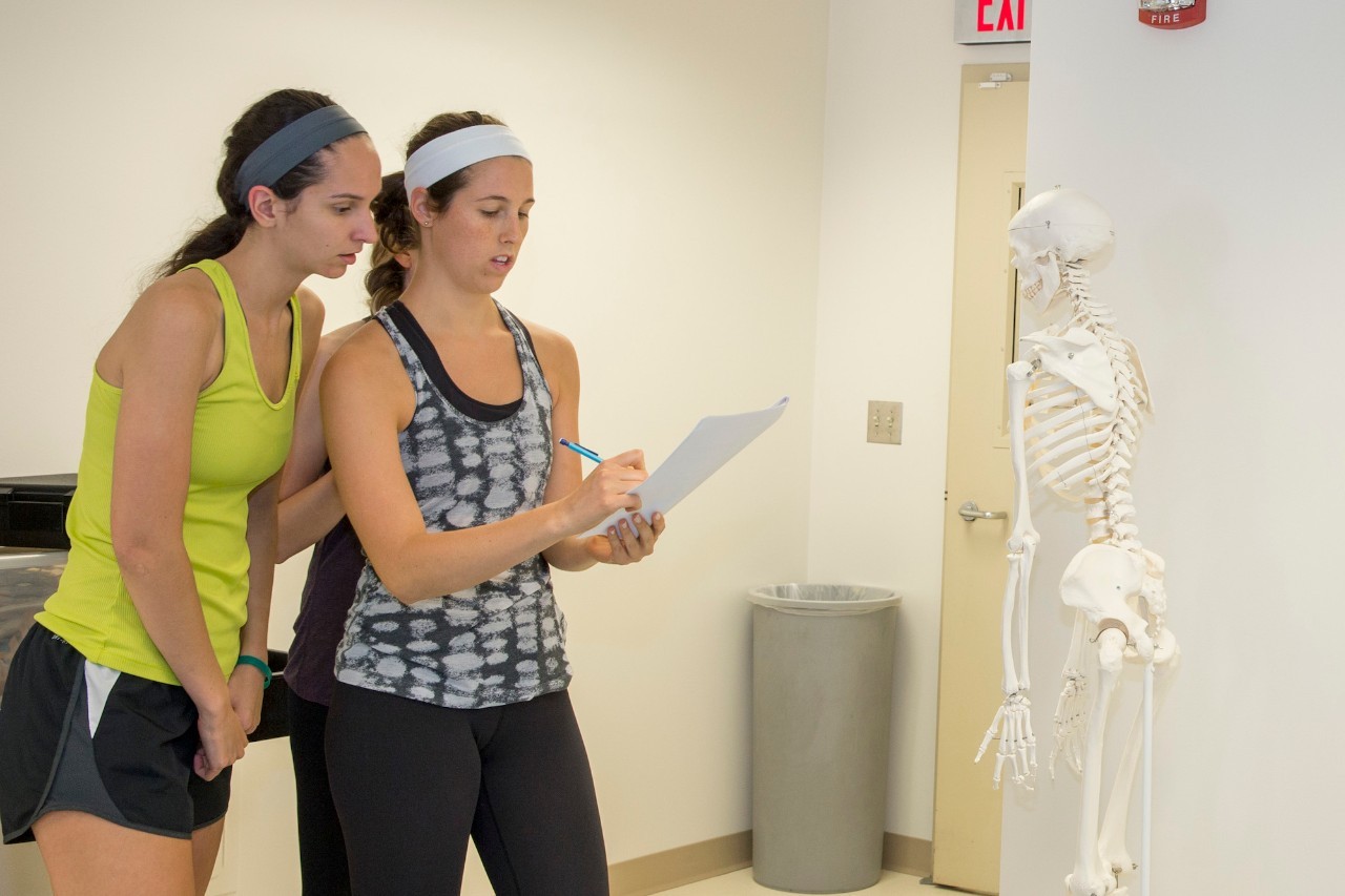 Two physical therapy students look over assignment in lab 