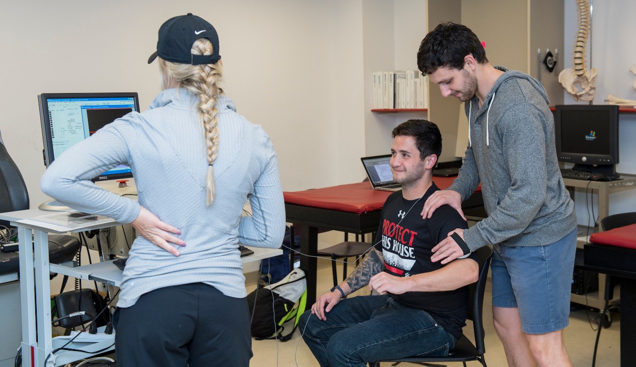 Students performing test on arm while recording results on computer